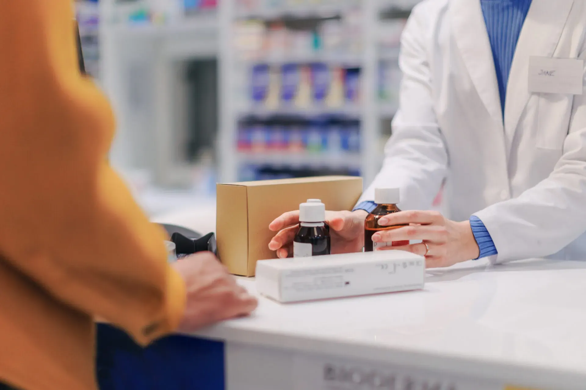 Pharmacist handing medicine bottles over the counter at Pan Pharmacy Birmingham