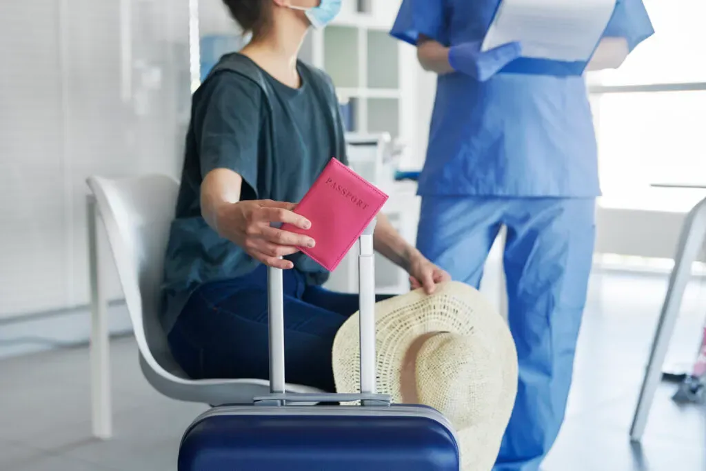Woman holding a passport and luggage before travelling, travel clinic at Pan Pharmacy Birmingham