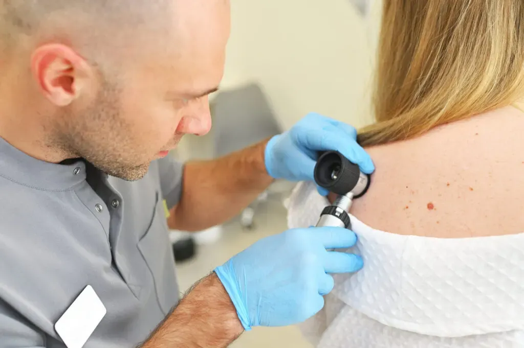 Clinician checking a mole on a patient's back with a dermatoscope at Pan Pharmacy Birmingham