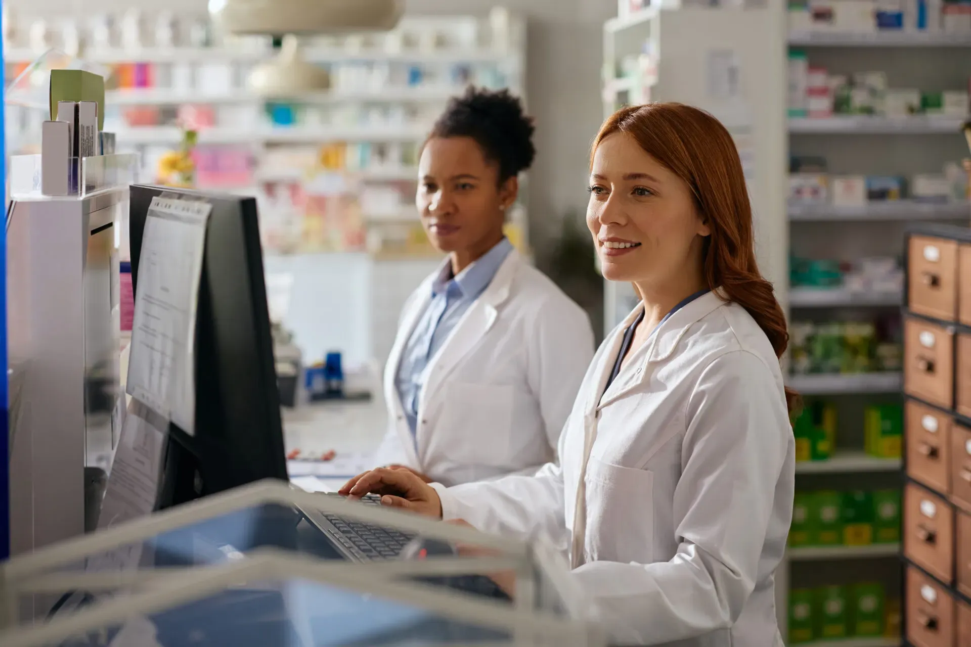 Smiling pharmacists working at a computer in the pharmacy, Vishnu Pharmacy