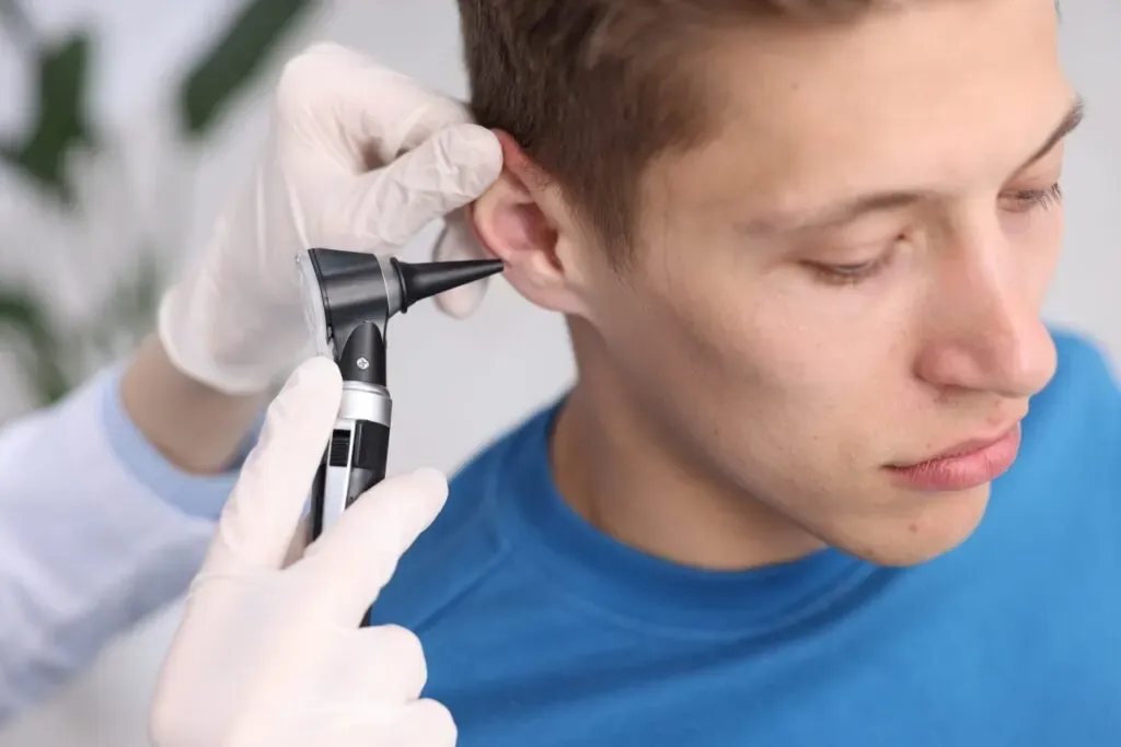 Clinician examining a man’s ear with an otoscope before ear wax removal at Pan Pharmacy Birmingham