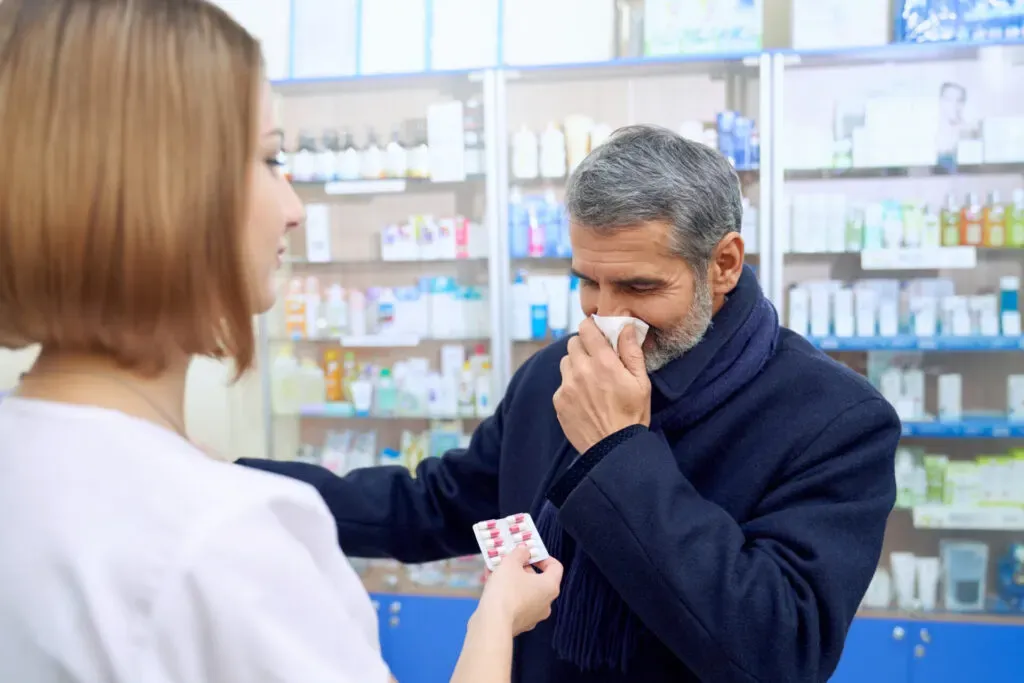Man with a cold buying medication from a pharmacist at Pan Pharmacy Birmingham