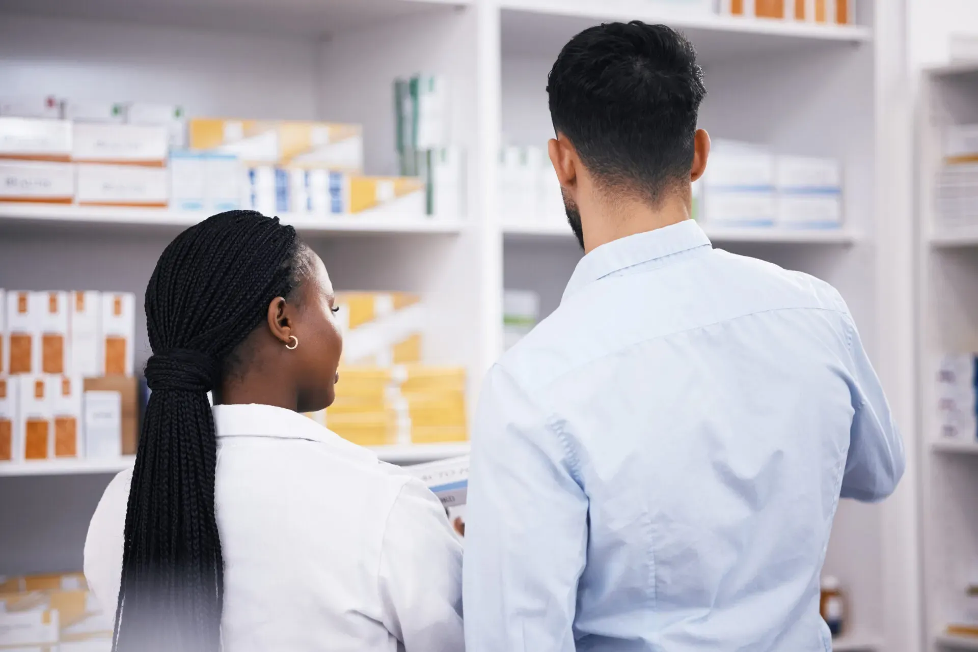Pharmacist looking at medicines on pharmacy shelves, Pan Pharmacy Birmingham