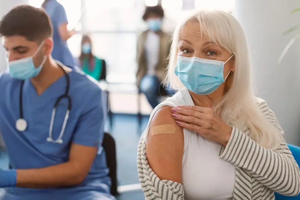 Woman in a face mask holding her arm after a vaccination at Pan Pharmacy Birmingham