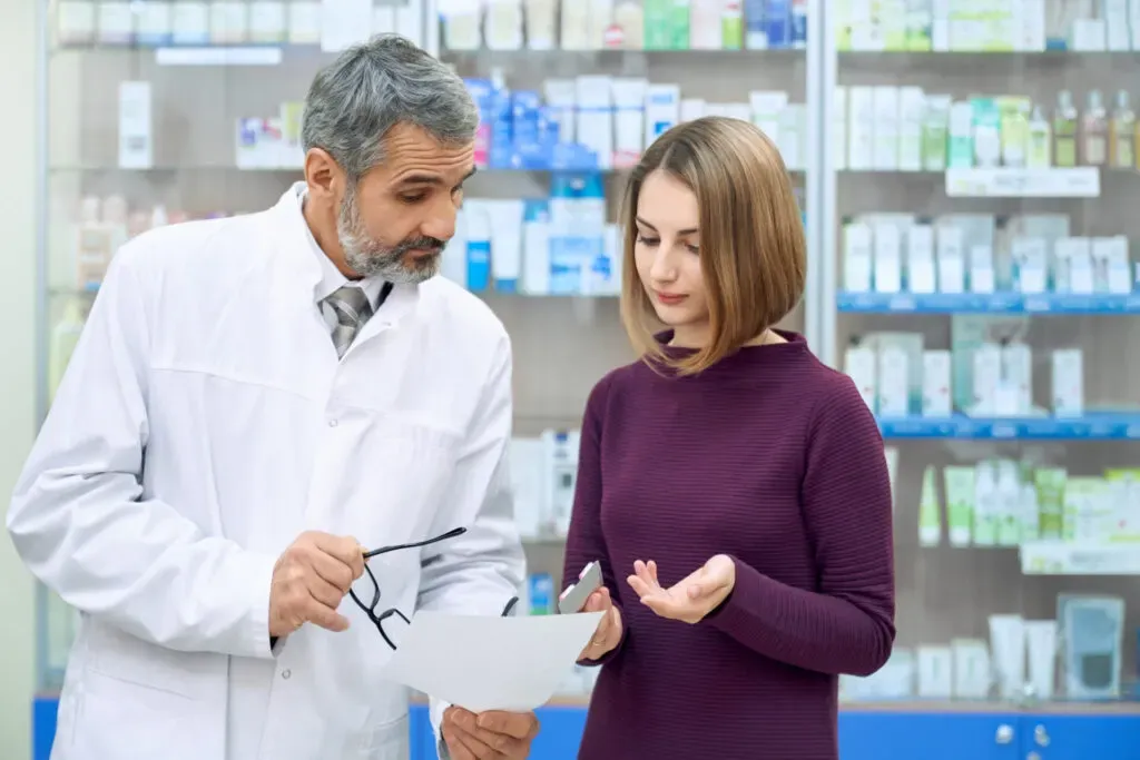 Pharmacist reviewing a prescription with a woman in the pharmacy aisle at Pan Pharmacy Birmingham