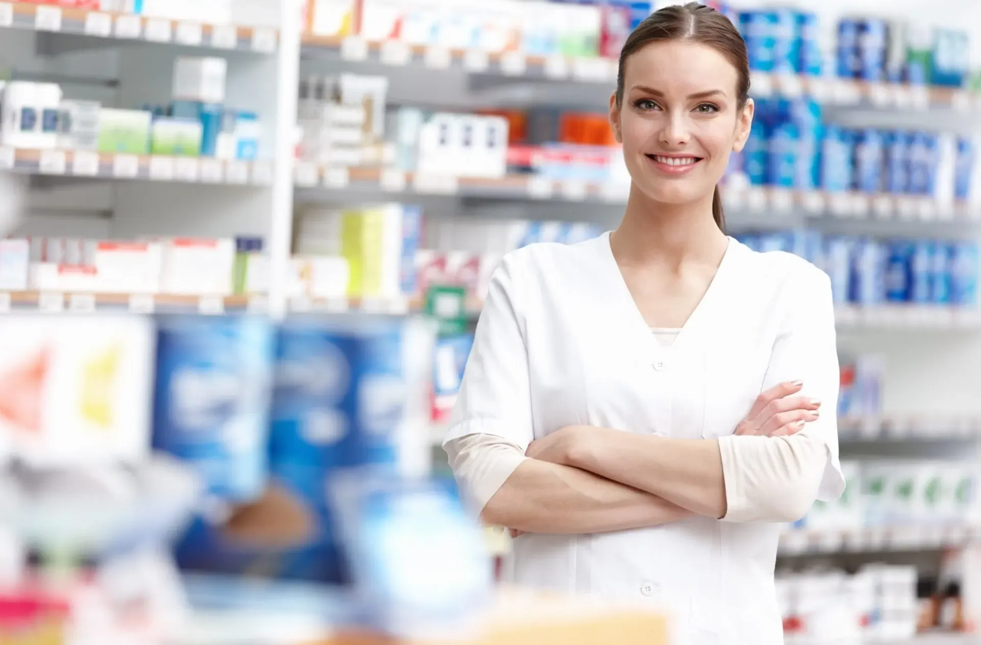 Smiling pharmacist standing in front of pharmacy shelves at Pan Pharmacy Birmingham