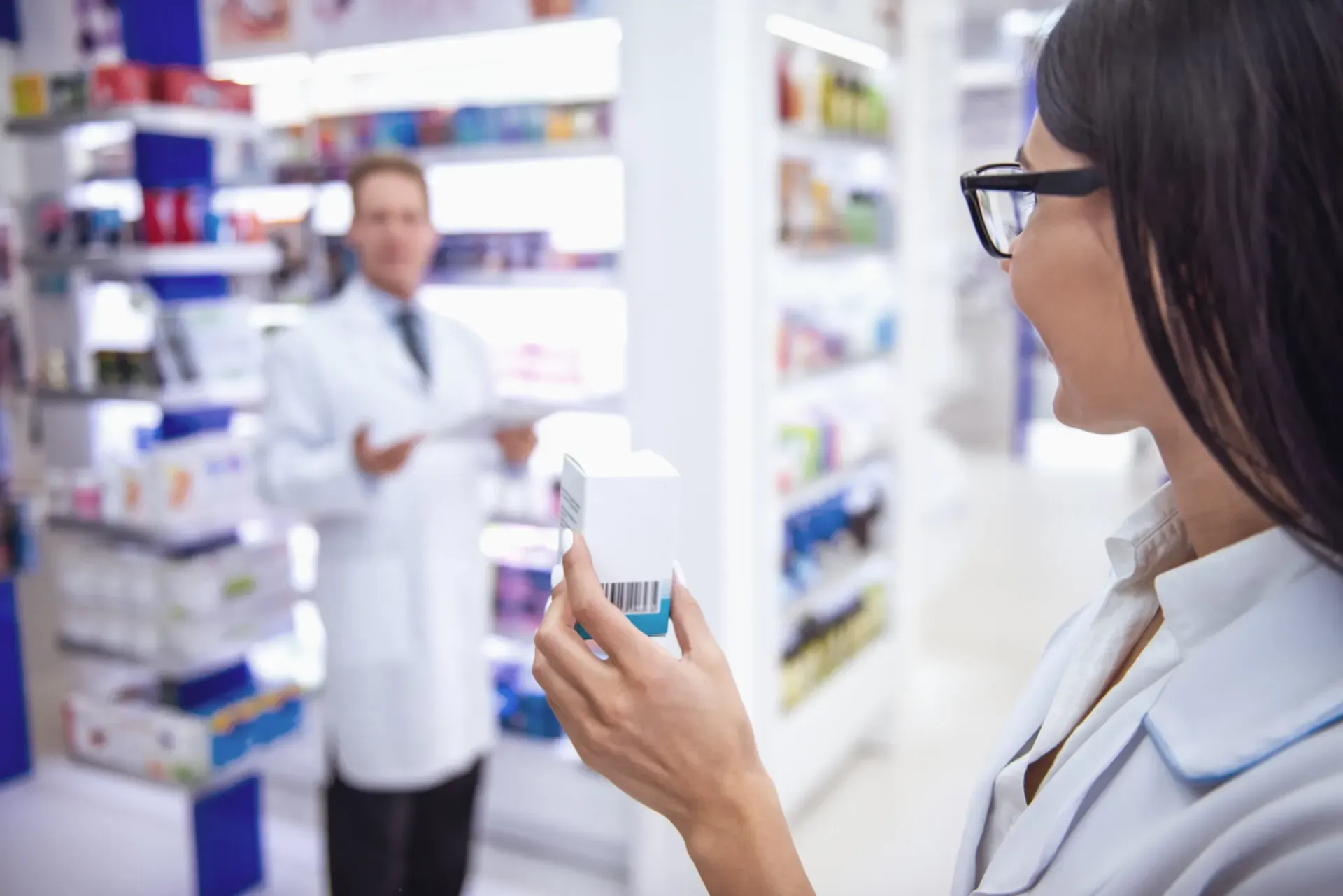 Pharmacist holding a medicine box in the pharmacy aisle, Pan Pharmacy – Garretts Green Lane