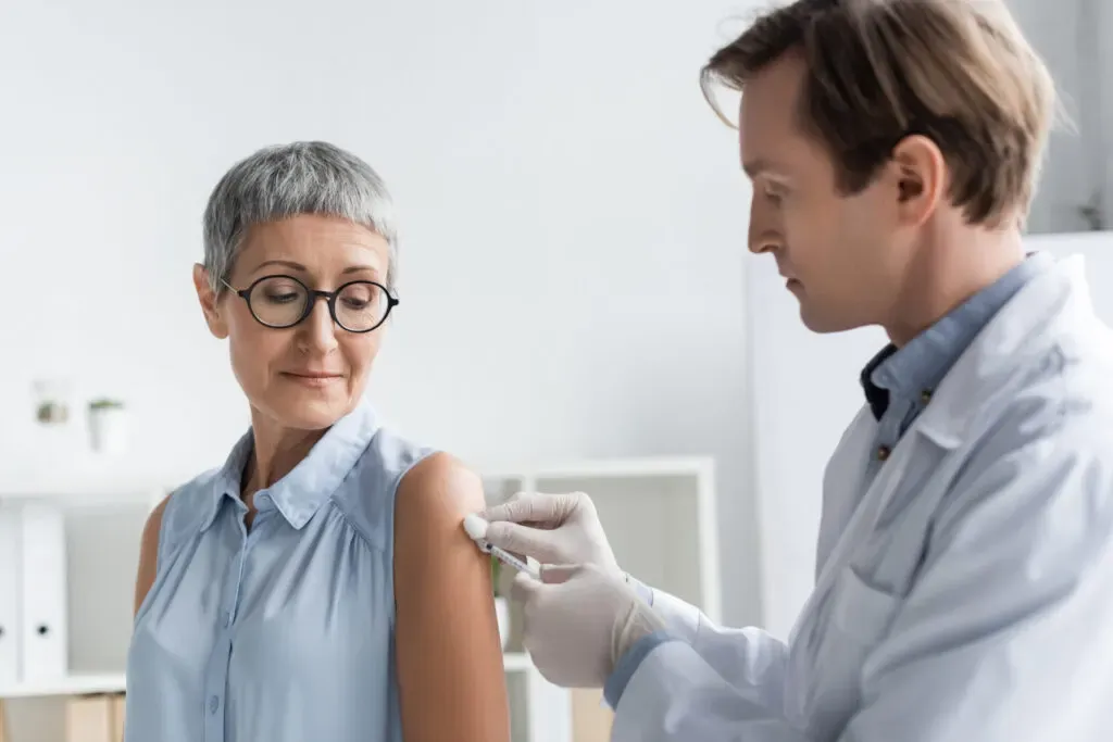 Healthcare worker giving a woman a vaccination in her upper arm at Pan Pharmacy Birmingham