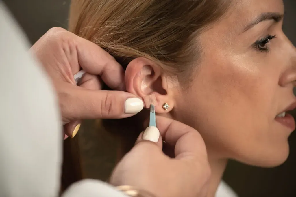 Woman having her ear pierced with a sterile stud at Pan Pharmacy Birmingham